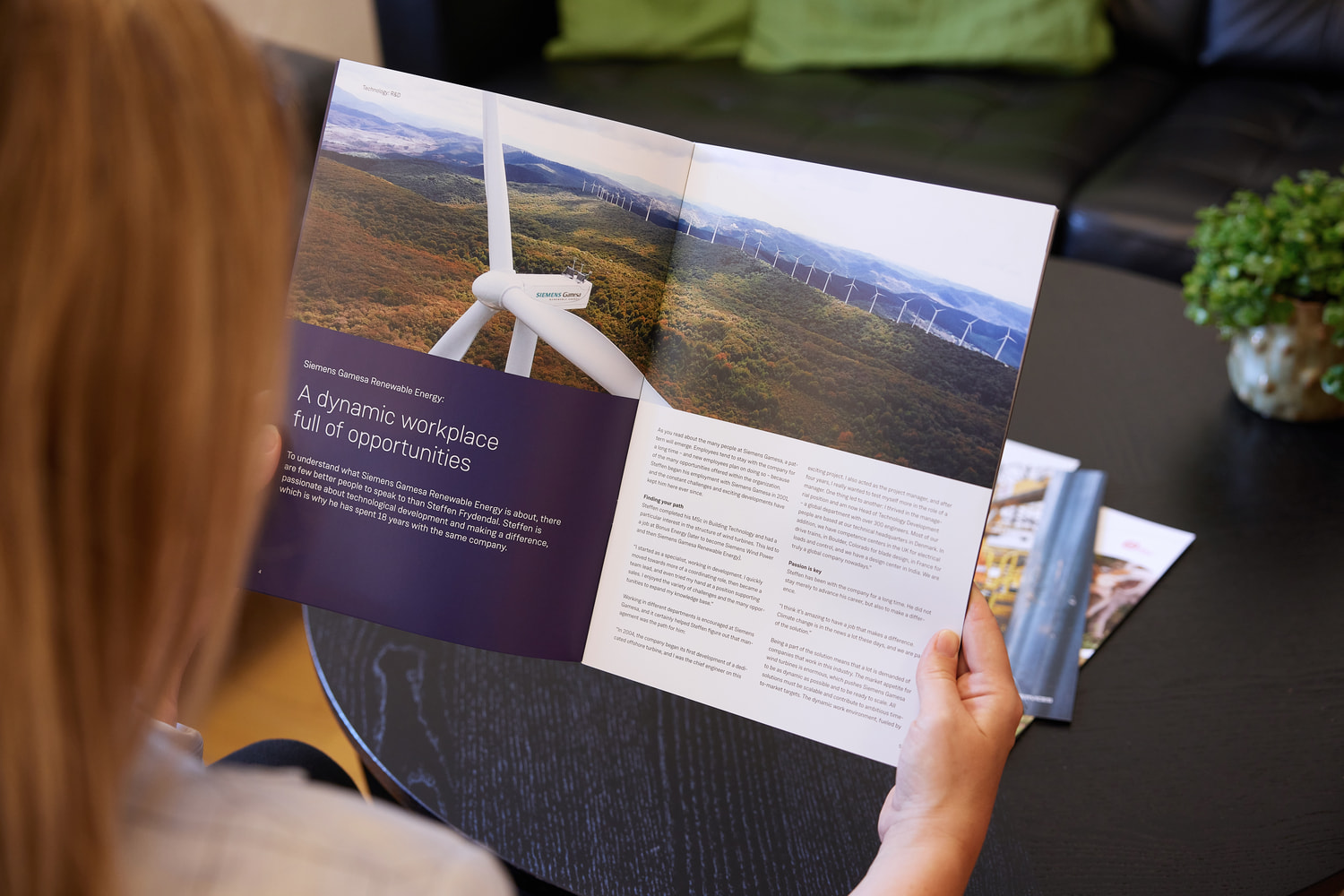 A woman is sitting and looking through a brochure at JS Danmark.